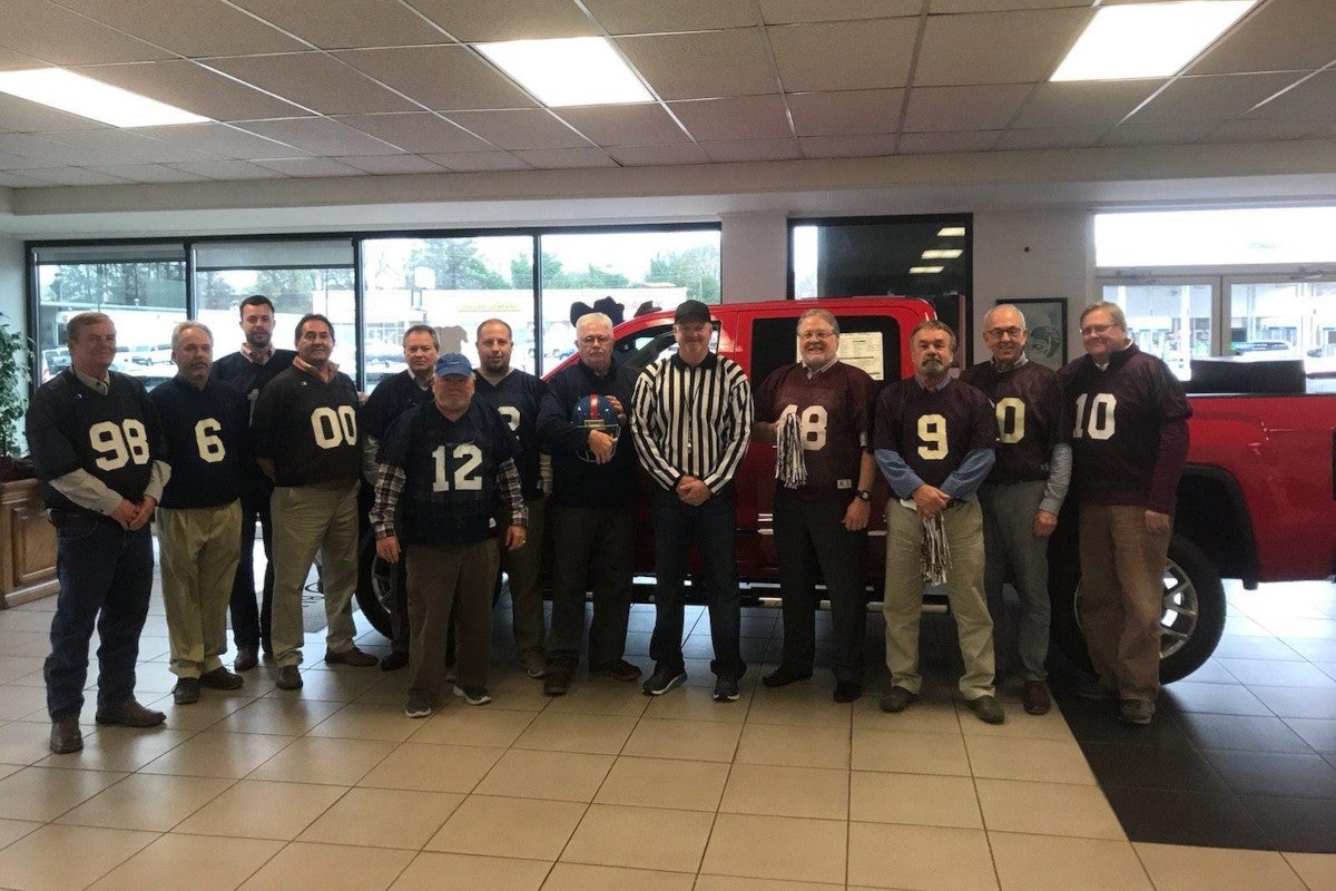 Team of men standing in front of truck at Dossett Big 4 Buick GMC