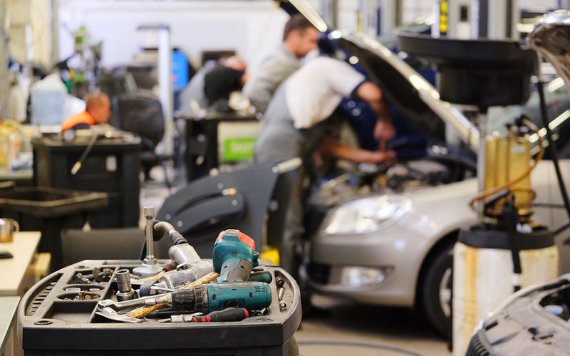 Men servicing cars in garage with tools