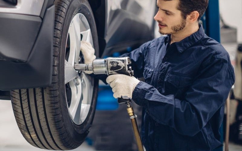 service technician tightening tire on car