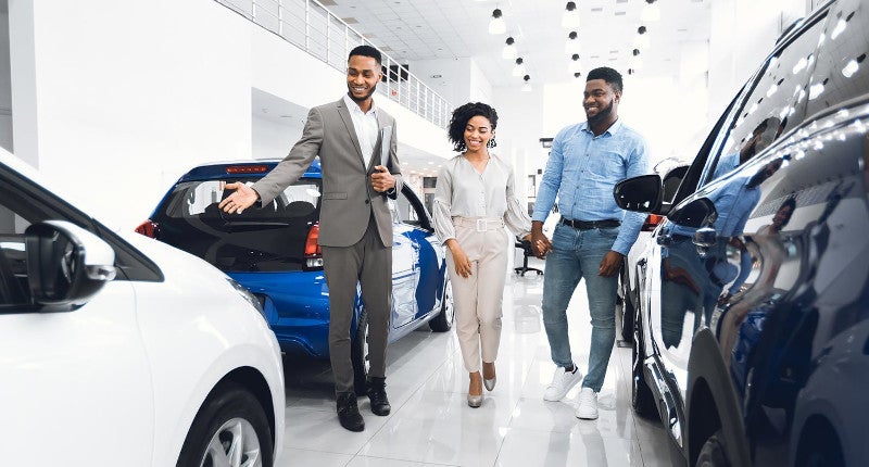 Car dealer showing couple cars in dealership display room
